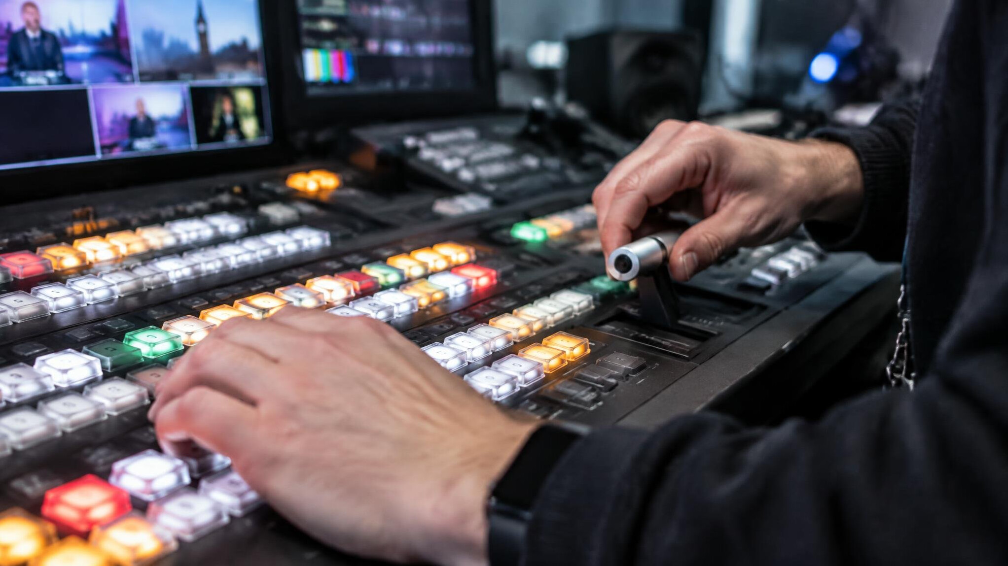 Close-up of hands operating a video switcher panel